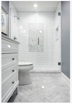 a white toilet sitting in a bathroom next to a walk in shower and vanity with drawers