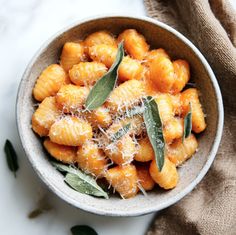 a bowl filled with pasta covered in cheese and sage