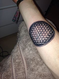 a man with a tattoo on his arm that has an image of a flower of life in it