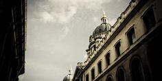 an old building with a steeple on the top and sky in the back ground