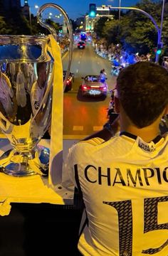 a man holding up a trophy on the side of a road with other people watching