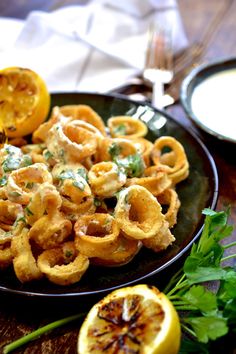 a black plate topped with onion rings and lemon wedges