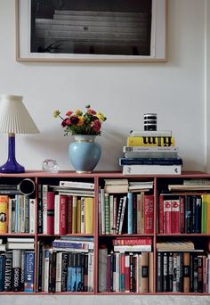 a bookshelf filled with lots of books next to a lamp and painting on the wall