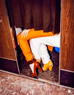 a woman sitting on top of a wooden chair next to a door with her legs crossed