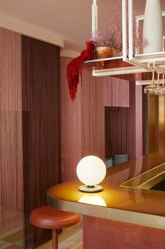 a table with a lamp on top of it next to a red chair and counter