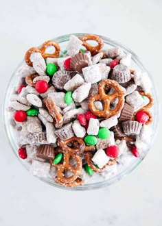 a glass bowl filled with christmas treats and pretzels on top of white counter