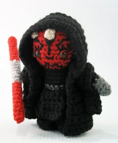 a crocheted darth vader doll holding a red and white object