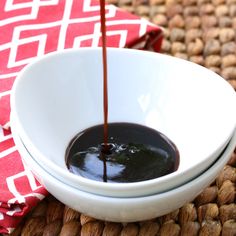 chocolate sauce being poured into a white bowl on top of a red and white napkin