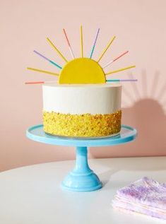 a white cake with yellow and blue frosting sitting on top of a table next to a napkin