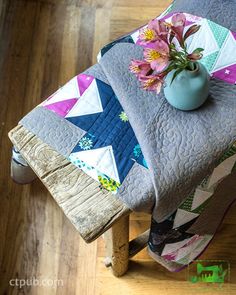 a table with a flower pot on top of it next to a wooden chair and pillow