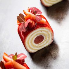 a roll with strawberries and leaves on it sitting next to another roll that is cut in half