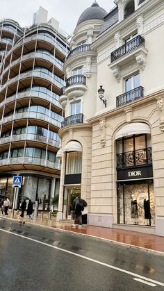 people walking on the sidewalk in front of a building with many windows and balconies