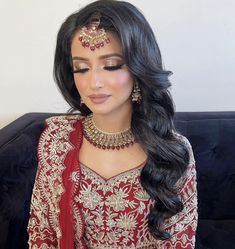 a woman wearing a red and gold bridal outfit