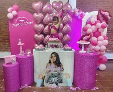 a woman sitting on top of a table surrounded by pink balloons and confetti