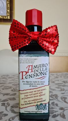 a bottle with a red bow on it sitting on top of a bedspread