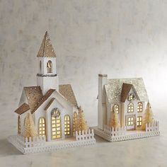 two small white houses with lights on them and one has a clock at the top