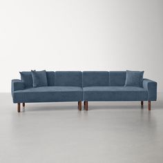 a blue couch sitting on top of a white floor next to a wooden leg chair