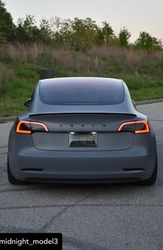 an electric car is parked on the side of the road in front of some grass