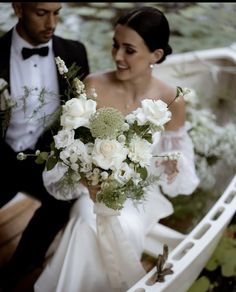 a bride and groom are sitting in a boat with their bouquets on the side