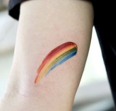 a rainbow tattoo on the leg of a woman's arm, which is painted in red, yellow, blue and green