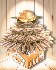 an origami christmas tree made out of money with a gold rose on top