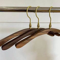 three wooden hangers are hanging on a metal rod