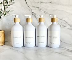 three bottles of shampoo sitting on top of a marble counter next to a potted plant