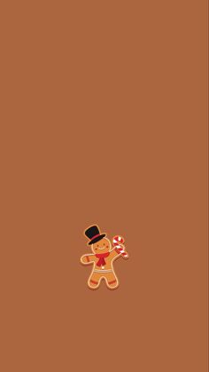 a gingerbread man with a top hat holding a candy cane in his hand on a brown background