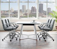 an office table with four chairs in front of large windows overlooking the cityscape