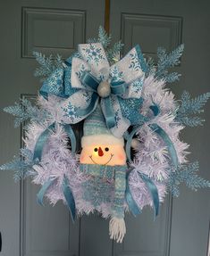 a blue and white wreath with a stuffed animal on it's head, hanging from the front door