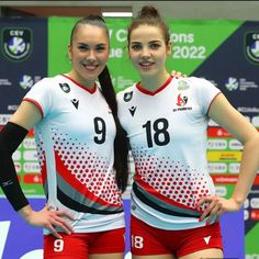 two women standing next to each other in front of a wall