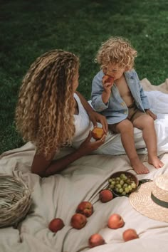 two women and a child sitting on a blanket eating apples