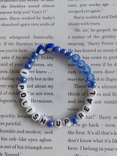 a blue beaded bracelet with words written in white and black on top of an open book