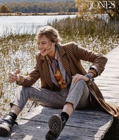 a man is sitting on a dock with his foot in the air and smiling at the camera