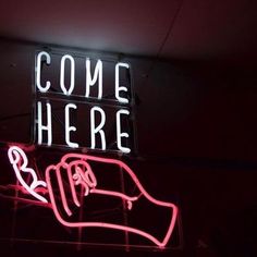 a neon sign that says come here with a hand