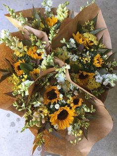 a bouquet of sunflowers and other flowers in brown paper wrapped around it's edges