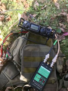 an electronic device attached to a backpack in the grass