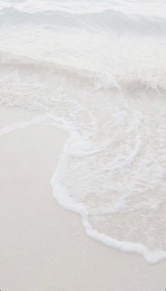 an ocean view with waves crashing on the beach and a surfboard in the foreground