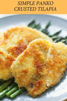 two pieces of fried chicken and asparagus on a plate with parmesan cheese