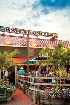 people are sitting at tables outside the crab and steak house