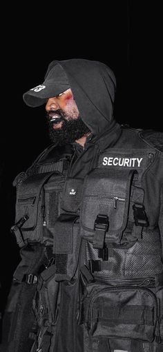 a man wearing a black security vest and hat