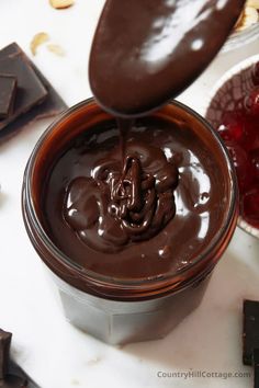 a spoon is pouring chocolate into a container