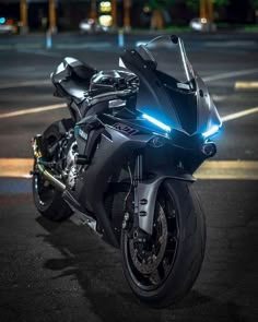 a black motorcycle parked in a parking lot at night with its lights on and the front light turned on