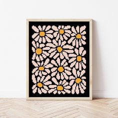 a cross - stitch pattern with daisies on black and white background in a wooden frame