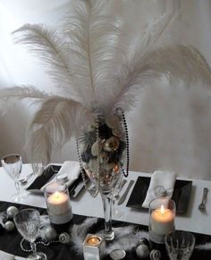 the table is set with candles, silverware and some feathers on top of it