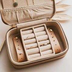 an open suitcase with jewelry inside sitting on a table