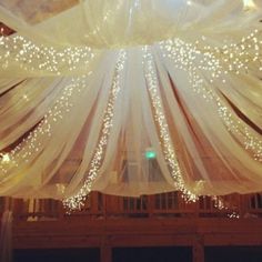 the ceiling is decorated with white lights and sheer draping for an elegant look