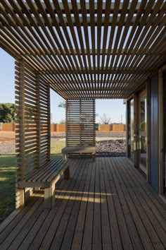 a wooden bench sitting under a pergolated roof on top of a wooden deck