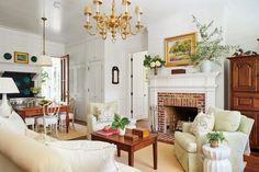 a living room filled with furniture and a fire place under a chandelier in front of a fireplace