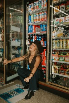 a woman sitting on the ground in front of a vending machine